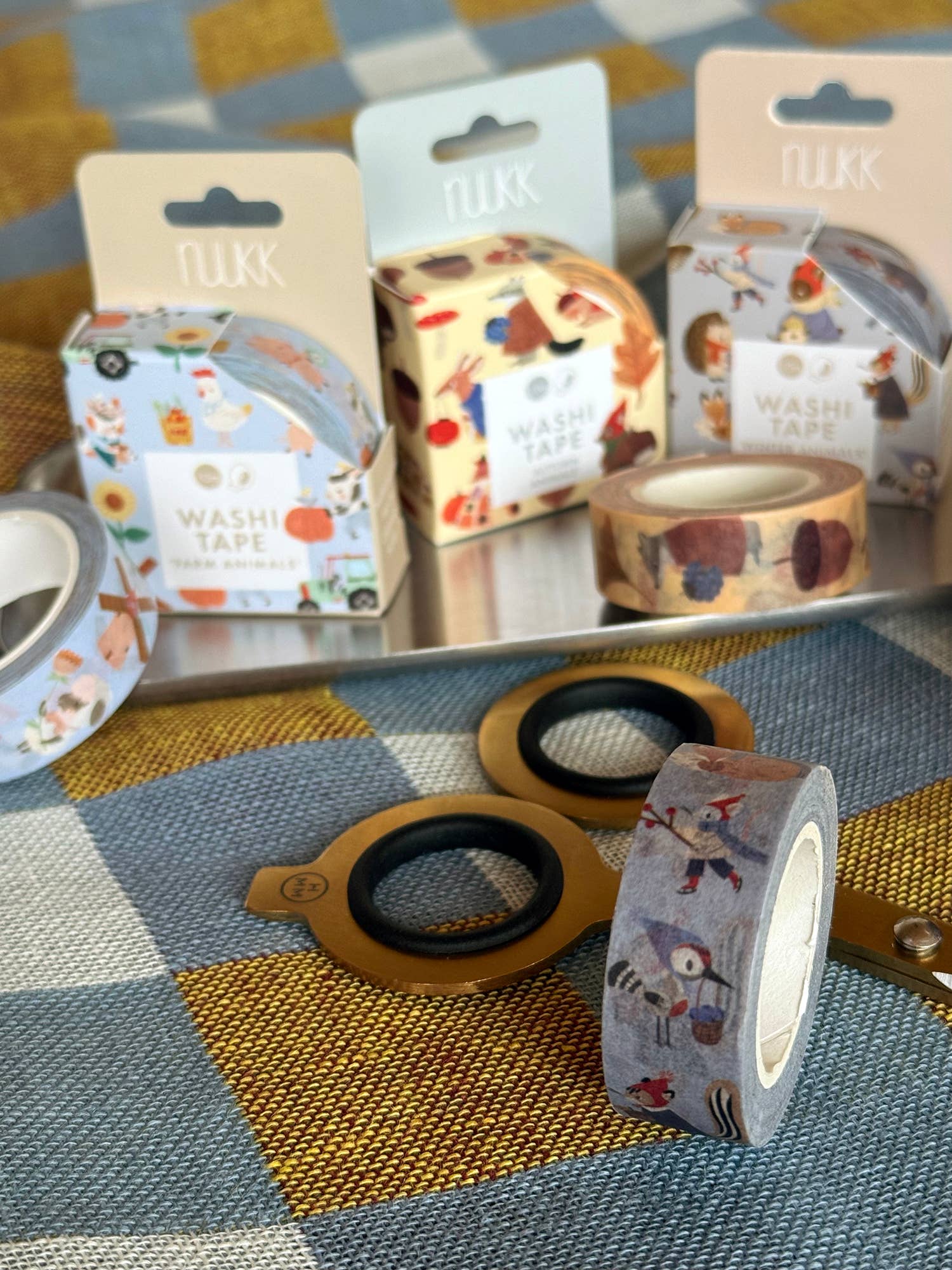 Decorative washi tape rolls on a textured surface with visible brand packaging.