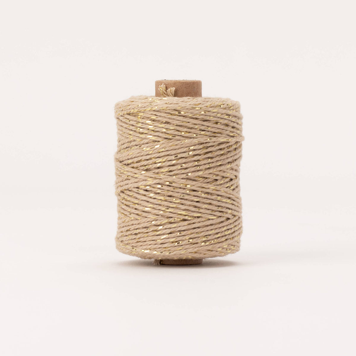 Spool of beige thread on a white background