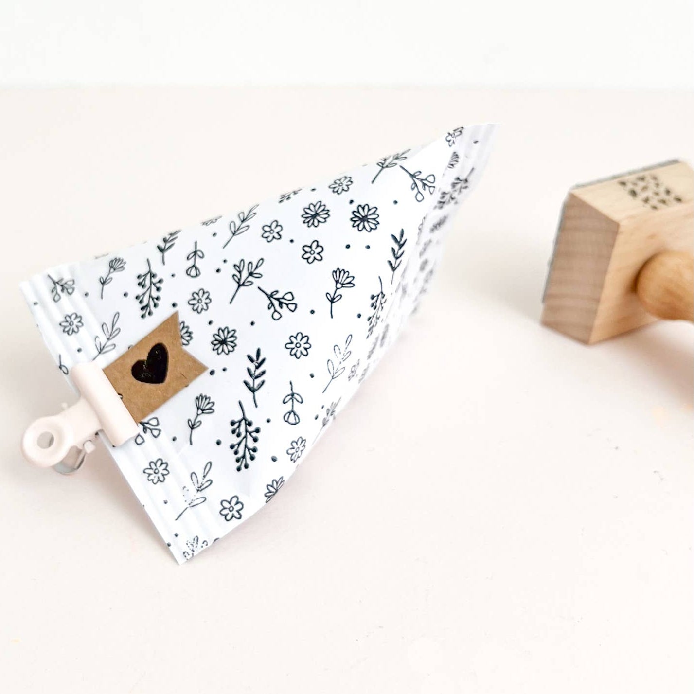 Small white container with black floral pattern on a white background