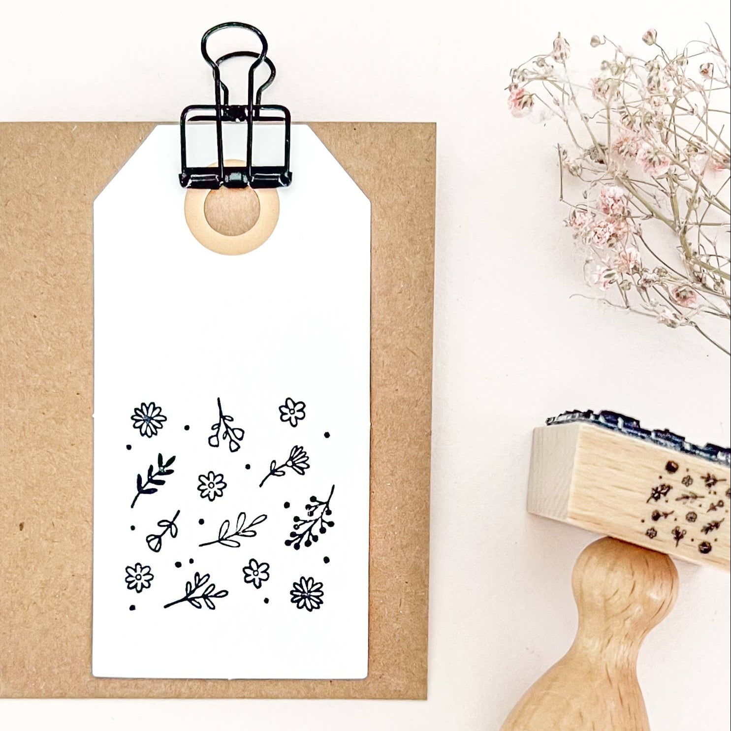 Floral stamp on a white background with a wooden handle and a small plant.