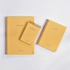 Three yellow notebooks with spiral binding on a white background