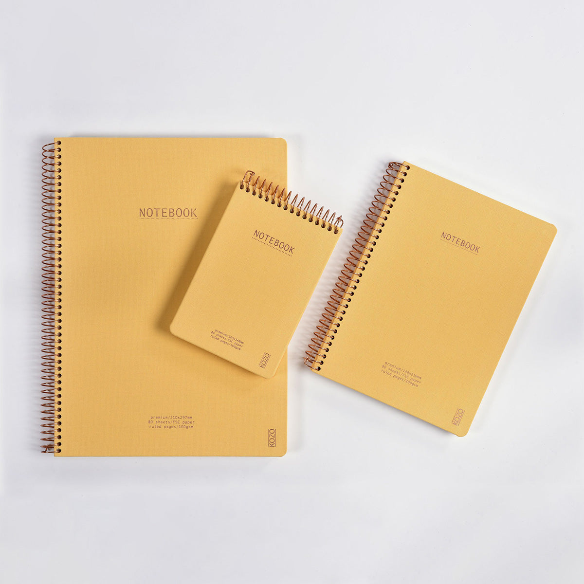 Three yellow notebooks with spiral binding on a white background
