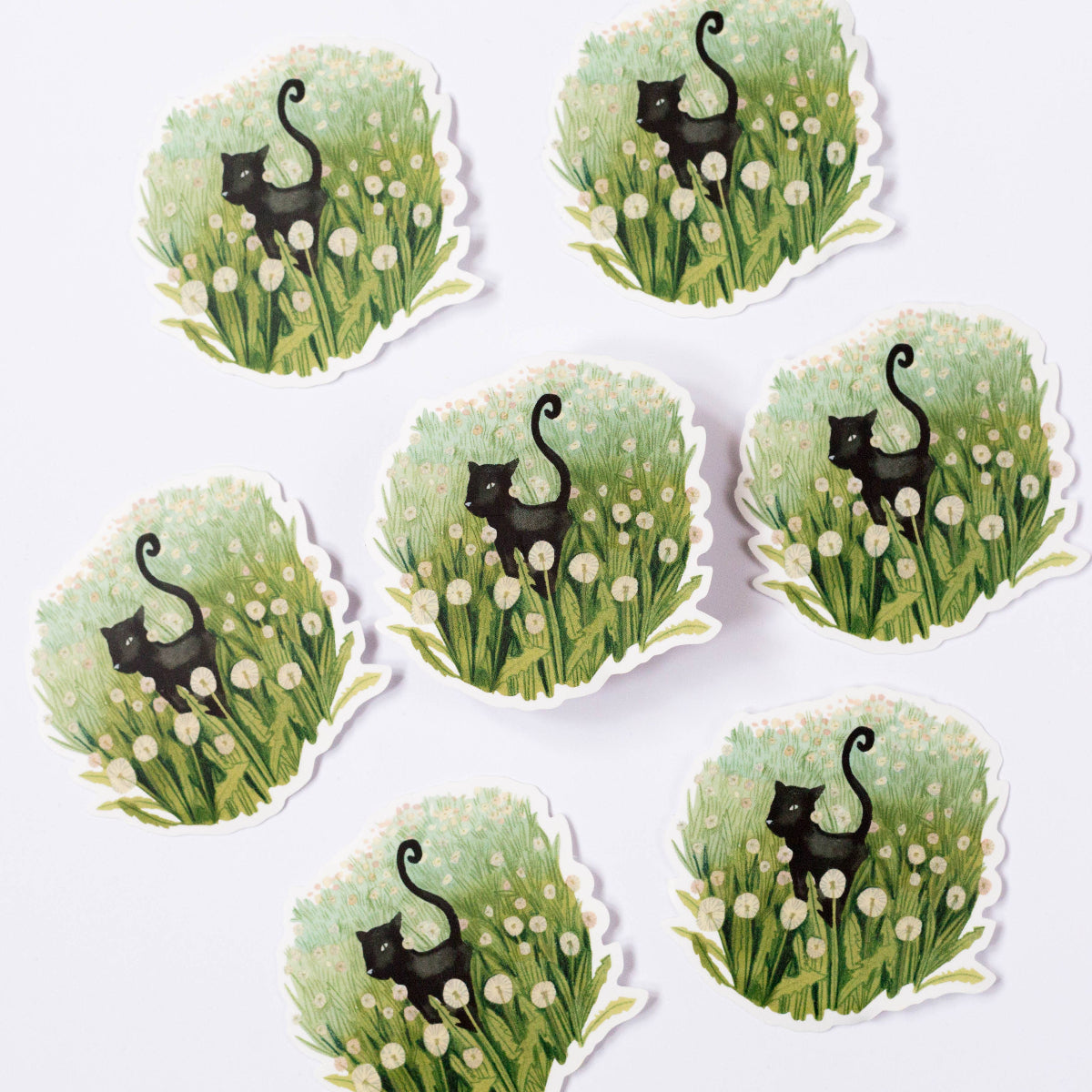 Set of eight stickers with black cats in grass and flowers on a white background
