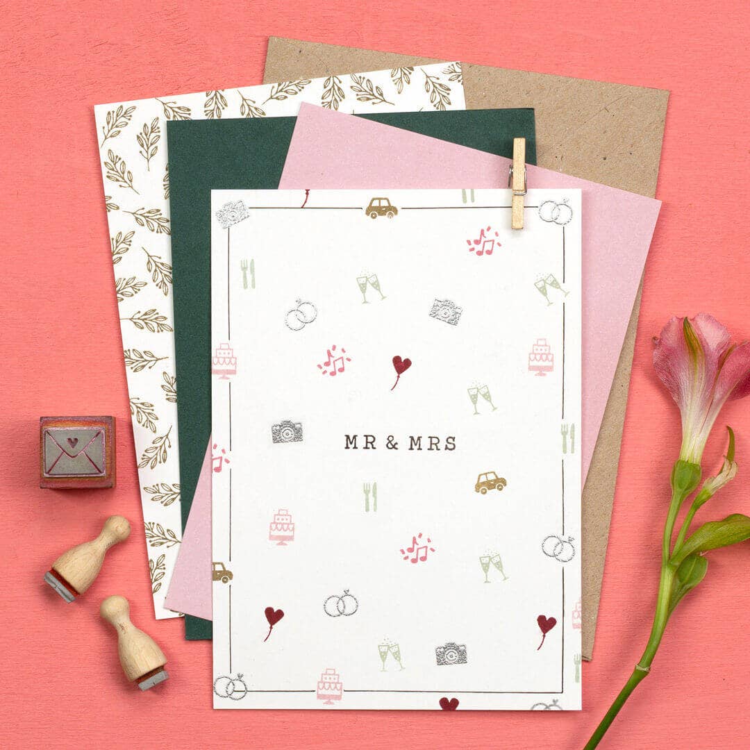 Set of stationery items including paper, envelopes, and stamps on a pink background