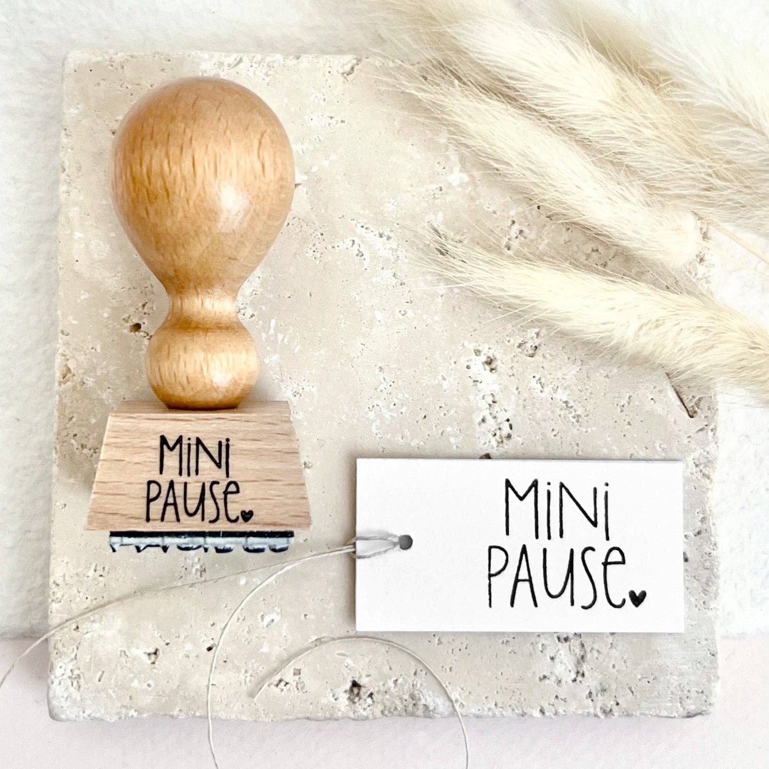 Wooden stamp with 'Mini Pause' text on a white background