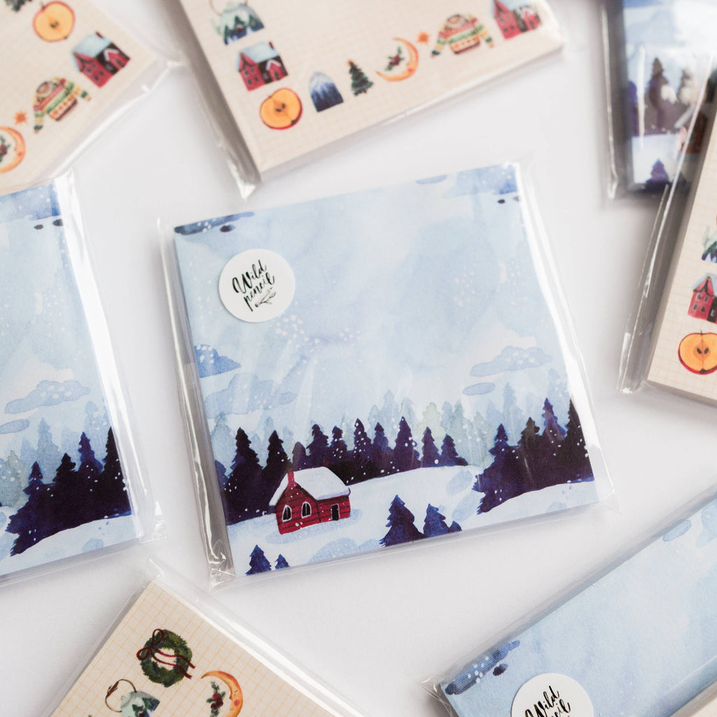 Collection of small sticky notes with winter-themed covers on a white surface