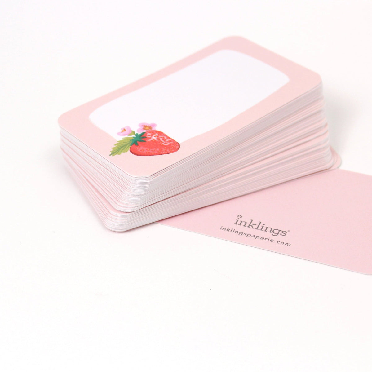 Stack of pink cards with a strawberry illustration on a white background, featuring the brand 'inklings'.