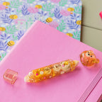 Decorative brownish correction and glue tape with 'Dream Big' text on a pink notebook with a floral patterned background.