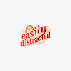 A die-cut sticker with the phrase 'easily distracted' in red and pink lettering, featuring a small rainbow and sun graphic above, shown on a plain light gray background.