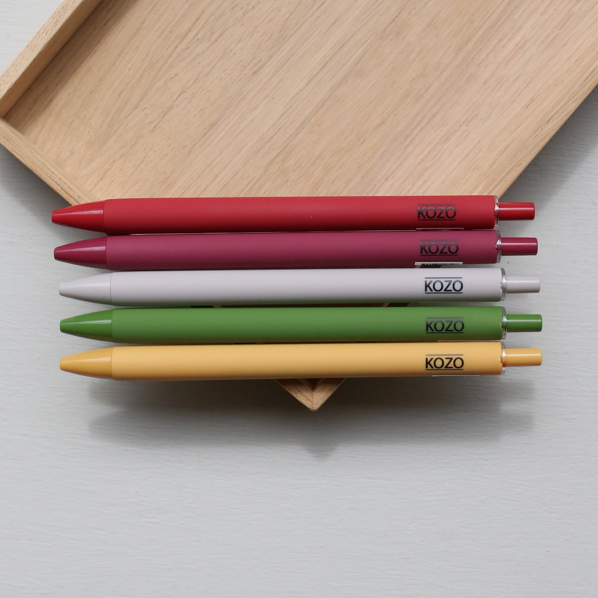 Five kozo ballpoint pens in different colours on a wooden tray