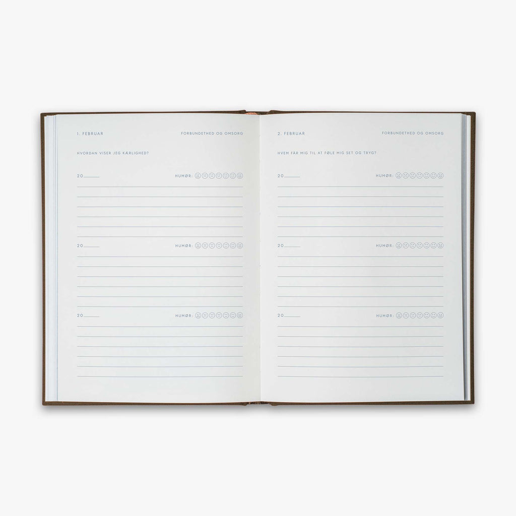 Open book from our Three Year Journal (Treårsdagbogen) with the daily prompts on a white background