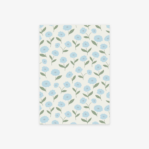 A rectangular sheet of paper with a repeating floral pattern of light blue flowers and green leaves on an off-white background, shown against a light gray studio backdrop.