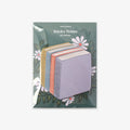 Pack of book stack-shaped sticky notes with floral design on a green background