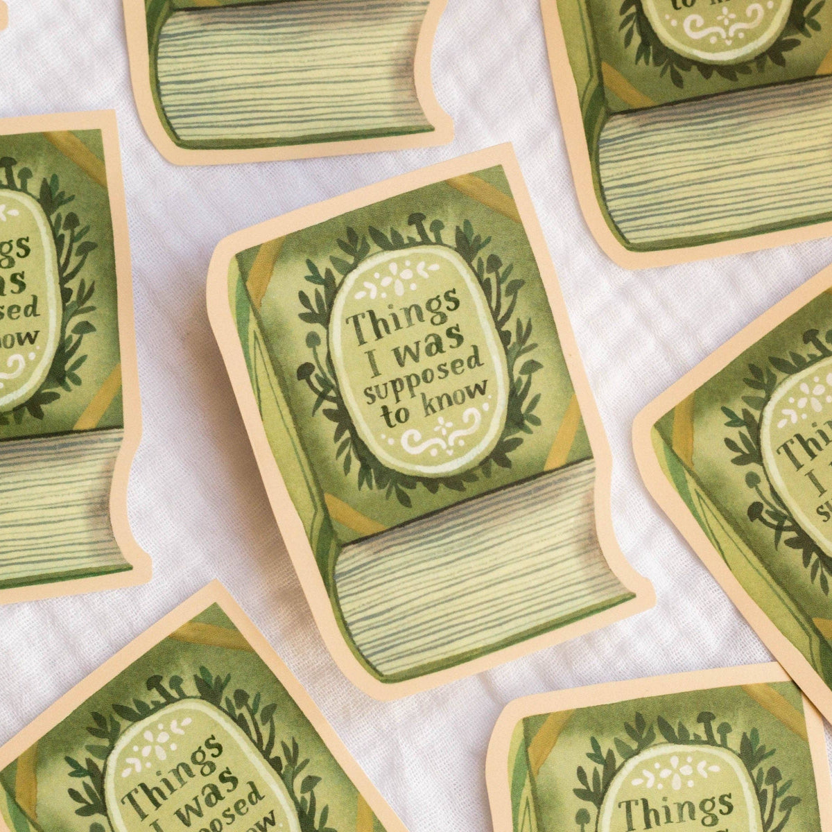 Green book-shaped stickers with 'Things I was supposed to know' text on a white background