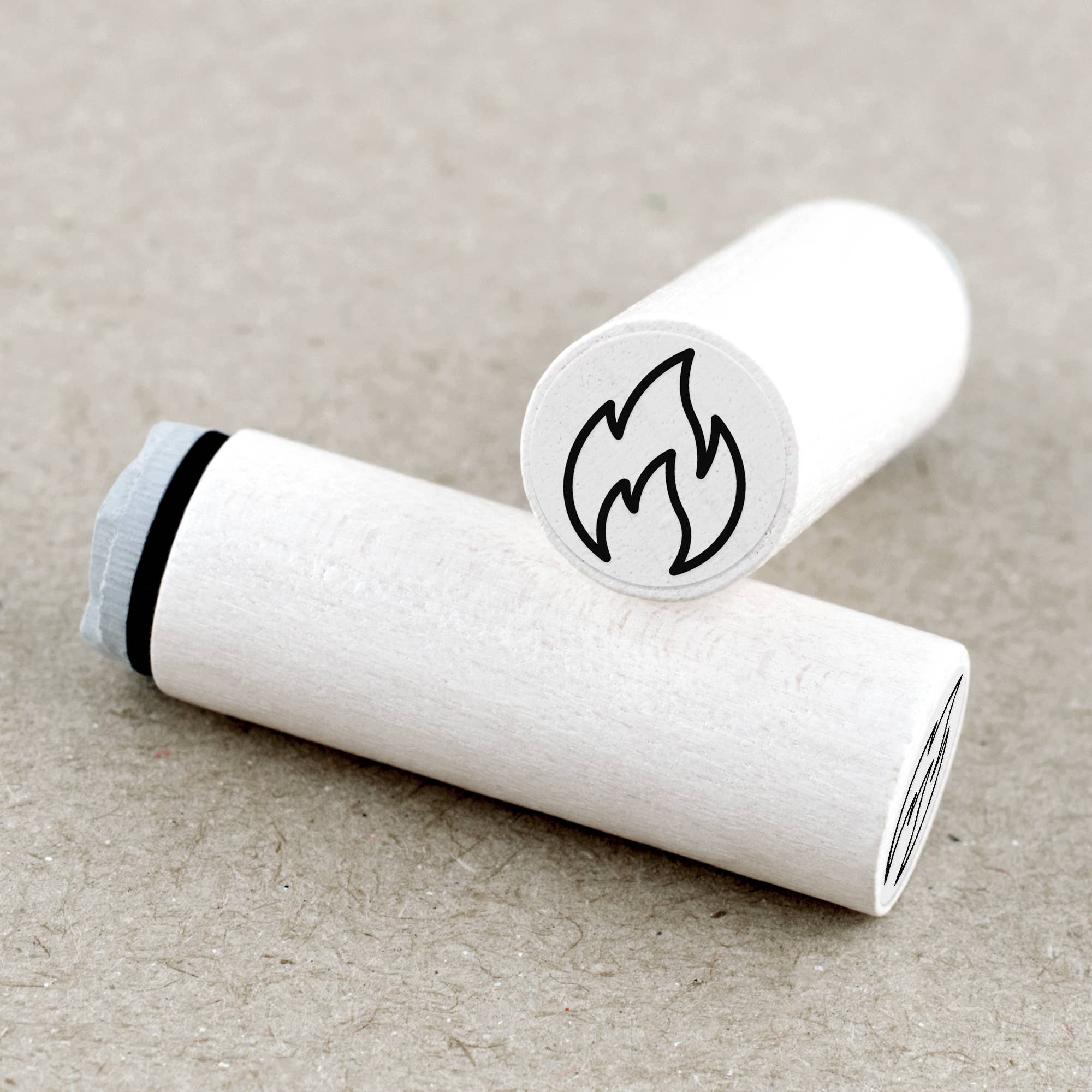 Two white rubber stamps with flame symbols on a beige background