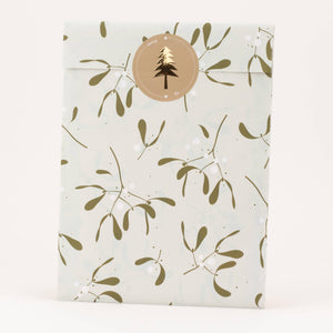 Packaging with a gold mistletoe pattern and a circular logo on a white background