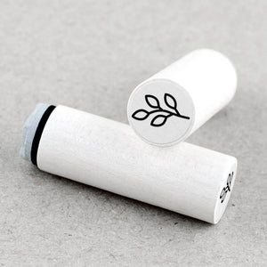 Two white rubber stamps with plant symbols on a beige background