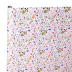 A roll of wrapping paper or fabric with a dense, multicolor floral and botanical pattern on a white background, shown against a plain white backdrop.